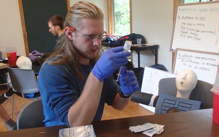 A person wearing gloves examine a vail during a wilderness first responder certification course. 